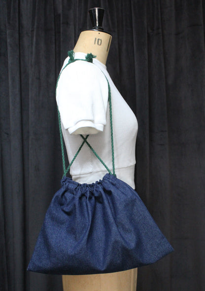 Mannequin wearing a white top with a blue drawstring bag on a black background